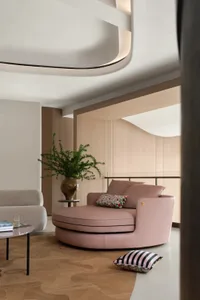 A modern living room with a round sofa, potted plant, and wooden flooring.