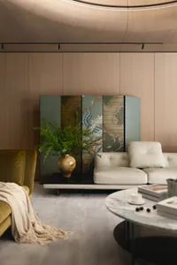 A modern living room featuring wood-paneled walls, a white leather sofa, and a marble coffee table with a vase of green plant
