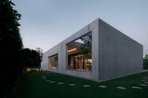 Modern residential exterior with large windows and concrete walls.