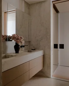 Modern minimalist bathroom featuring marble walls and flooring, with a floating sink and floral arrangement.