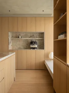 Modern minimalist residential kitchen featuring wooden cabinets and a marble backsplash.