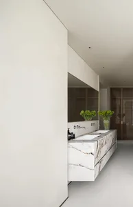 A modern bathroom with a marble countertop featuring two sinks and a minimalist design.