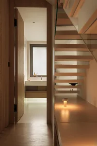 A modern bathroom featuring a minimalist design with wooden elements and sleek white surfaces.