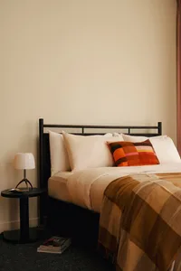 A cozy bedroom with a bed, pillows, and a throw blanket.