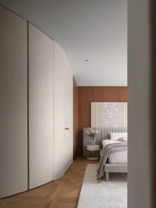 A modern bedroom with white cabinets and a wooden headboard featuring a geometric pattern.
