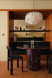 Modern kitchen with a round marble dining table, black furniture, and a chandelier.