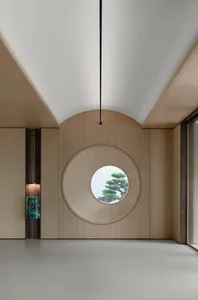A modern living room with a circle window and wooden panels.
