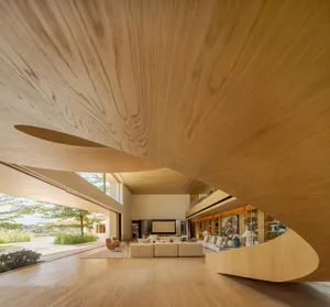 A modern living room featuring wooden walls and floors, with a large open space and natural light.