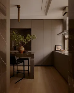 Modern kitchen with marble countertops, wood flooring, and minimalist design.