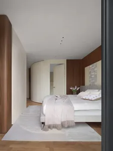Modern, minimalist bedroom featuring wooden paneled walls, white closets, porcelain floor tiles, and a gray rug. The space is