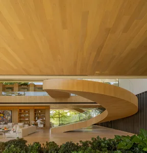 Interior design of a modern minimalist living room featuring a curved wooden staircase, extensive use of natural light, and a