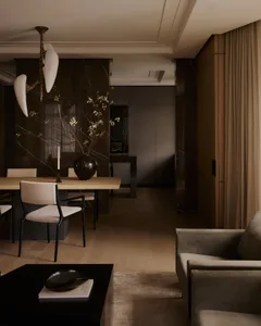 A modern residential dining room with a wooden floor, marble accent wall, and upholstered furniture.