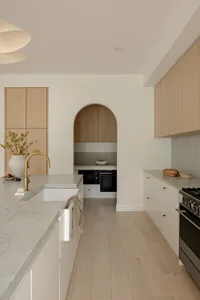 A minimalist kitchen with marble countertops and wooden cabinets.