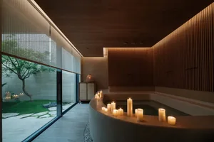 A serene spa interior featuring minimalist design with wooden elements, candles, and stone surfaces.
