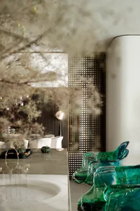 A modern living room featuring green accent glass furniture and glass table with geometric patterns.