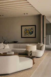 Modern living room featuring an orange armchair, neutral-toned sofa, and abstract wall art.
