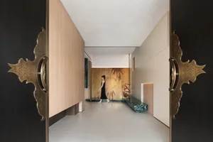 A sleek, modern corridor with glass walls and wooden flooring featuring a woman walking.