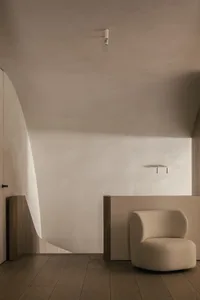 A minimalist interior space with a beige armchair and neutral tones.