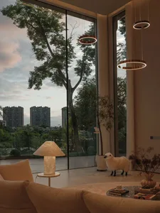 A modern minimalist residential living room with large windows overlooking a tree and cityscape.