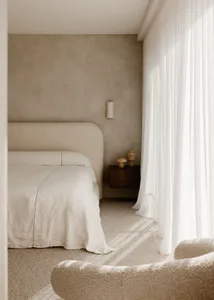 A minimalist bedroom featuring textured furniture and sheer curtains.