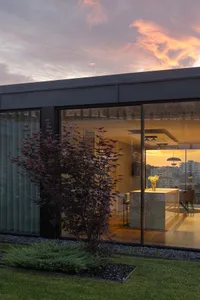A minimalist house exterior featuring large glass windows and a modern design.