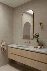 Modern bathroom featuring a marble countertop, concrete sink, oak vanity, brass fixtures, and a minimalist design.