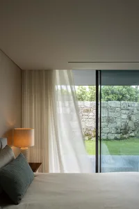 A modern bedroom featuring curtains and minimalist design.