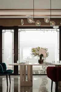 A modern dining room featuring a marble table and chairs, with a vase of flowers as a centerpiece.