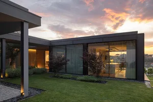 Modern house exterior featuring large glass walls and a sleek, contemporary design.