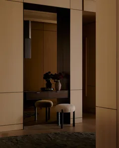 A modern interior with a wooden desk and stool, featuring a vase with flowers on top.