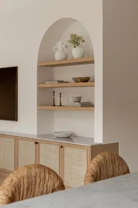 A modern kitchen featuring marble countertops and timber cabinets with woven accents.