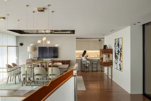 Modern living, dining, and kitchen area featuring wooden floors, glass tables, and metal furniture.