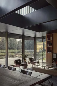 A modern living room featuring concrete and glass elements with a view of nature.