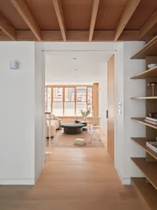 A modern minimalist living room with glass windows, wood flooring, and a mix of concrete and glass elements.