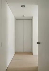 A minimalist interior with white paneled walls and a light wood floor.