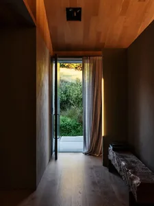 現代簡約玄關，木質地板、玻璃門與紋理石材長椅，搭配自然戶外空間