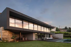 Modern residential house featuring a glass facade and concrete elements, viewed from the exterior.