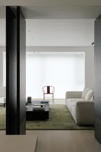 A modern living room featuring a white sofa on a green carpet with wooden panels and a minimalist design.