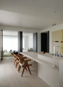 A modern kitchen and dining counter with wooden chairs and minimalistic design elements.