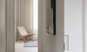 A minimalist living room featuring a modern woven chair against a textured fabric backdrop.