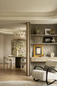 A modern living room featuring a wooden shelf with various decorative items, white fur upholstery chair, and a neutral color 