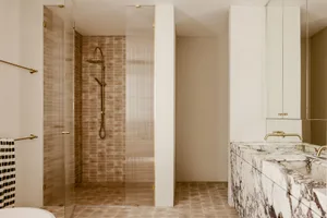 Modern bathroom featuring marble countertops and glass shower enclosure.
