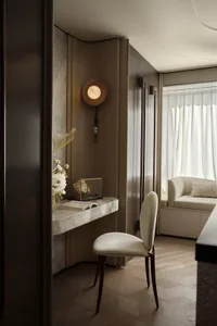 A modern minimalist office with a marble wall, a sleek desk, and a white upholstered chair.
