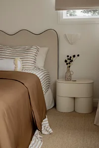A modern minimalist bedroom with a comfortable bed and a unique nightstand.