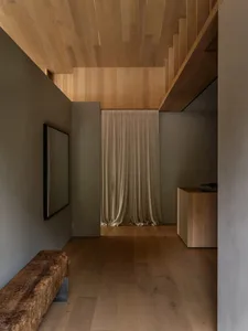 A modern minimalist interior with wooden elements, including a curtain and a wooden bench.