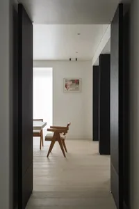Modern minimalist interior featuring a wooden chair and table with a wall-mounted abstract artwork.