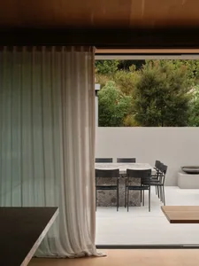A modern outdoor dining area featuring a concrete table surrounded by black chairs.
