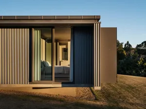 Modern residential exterior featuring metal clad panels and a sliding glass door.