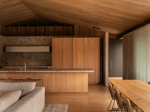Modern residential kitchen featuring wooden cabinets and a wooden dining table with chairs.