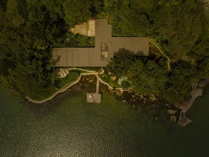 Modern seaside residence featuring concrete architecture and lush greenery.